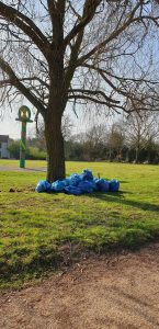 large pile of collect rubbish bags under a tree